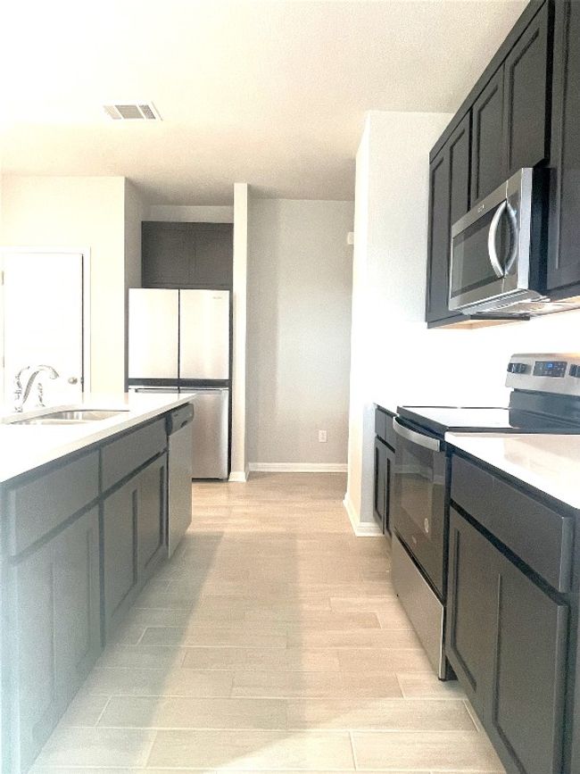 Kitchen featuring appliances with stainless steel finishes, light wood-style floors, and light countertops | Image 8
