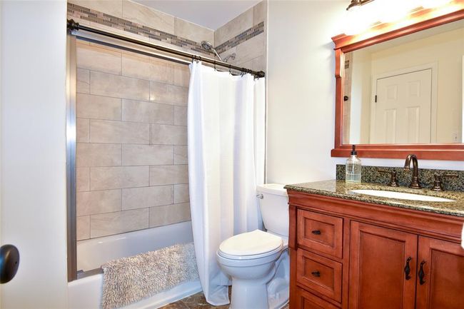 Bathroom with toilet, vanity, and shower / bathtub combination with curtain | Image 11