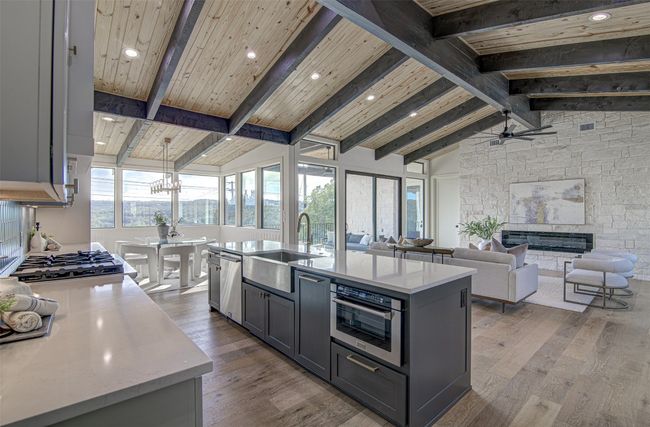 Kitchen with a sink, appliances with stainless steel finishes, wood finished floors, a stone fireplace, and ceiling fan | Image 6