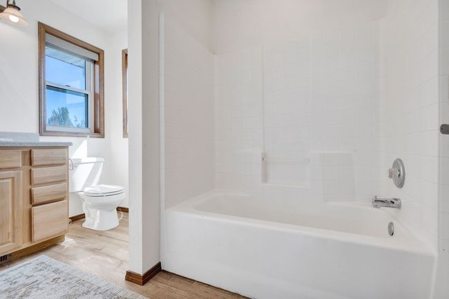 Full bath with toilet, wood finished floors, washtub / shower combination, and baseboards | Image 42