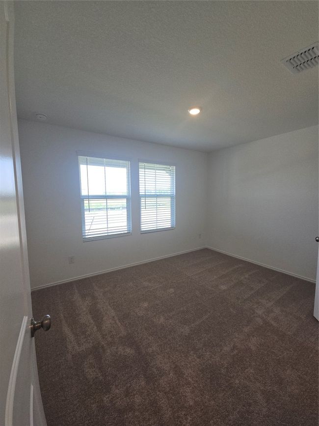 Empty room with dark colored carpet, baseboards, recessed lighting, and a textured ceiling | Image 14