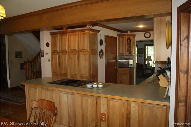 Dining room, looking into kitchen, through to the sunroom, with stairs to upper and lower levels to the left. | Image 10