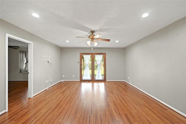 Living area has recessed lighting and double doors that lead to the covered patio and beautiful large backyard. The room opening pictured leads to the primary bedroom. | Image 9