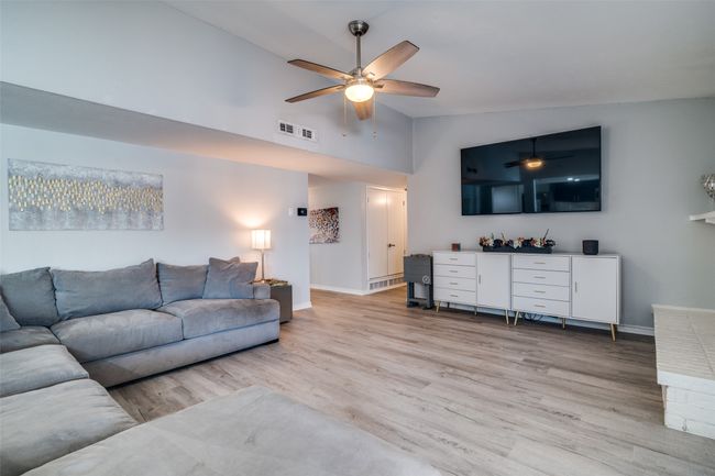 Living room with a ceiling fan, light wood finished floors, baseboards, and high vaulted ceiling | Image 6