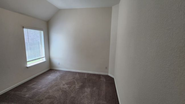 Empty room featuring dark colored carpet, lofted ceiling, and baseboards | Image 20