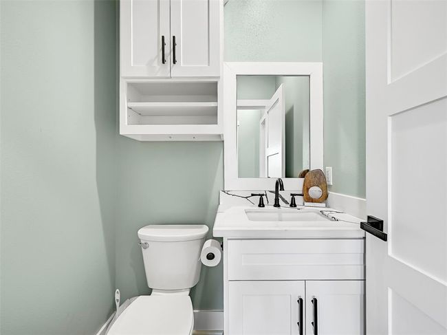 You'll appreciate the convenience of this half bathroom that is situated just off the main living area, featuring quartz countertops, modern fixtures, and built-in storage. | Image 17