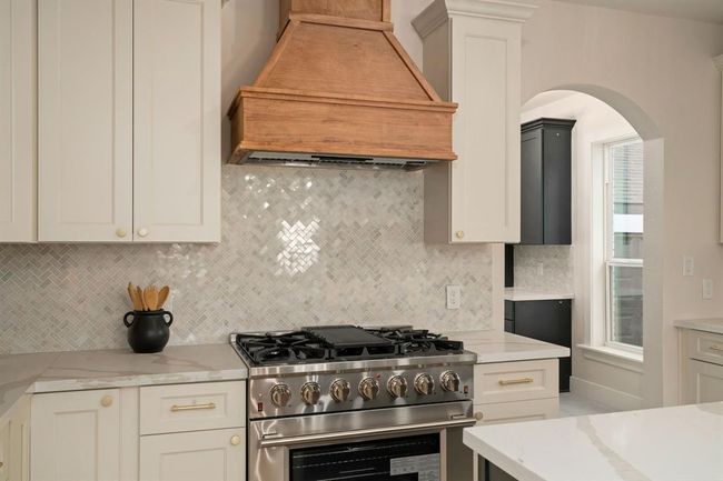 Custom 42" cabinets with gold hardware, a high-end stainless steel gas range, and a custom vent hood make cooking a pleasure. | Image 15