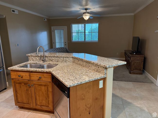 Kitchen with a sink, dishwasher, a ceiling fan, crown molding, and light stone counters | Image 5