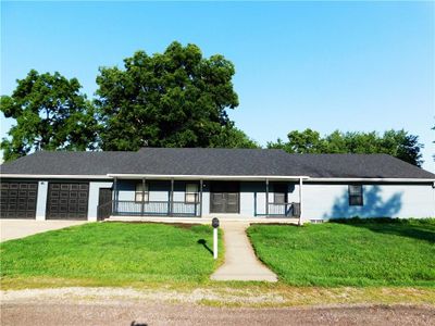 Ranch-style home with a garage, a front yard, and covered porch | Image 1