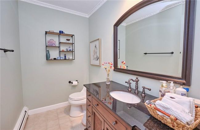 Bathroom with ornamental molding, tile patterned floors, baseboard heating, vanity, and toilet | Image 25
