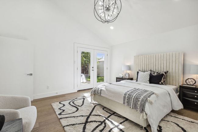 Bedroom with wood finished floors, high vaulted ceiling, recessed lighting, access to outside, and a notable chandelier | Image 22