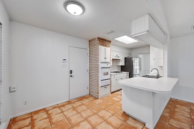 Kitchen featuring white cabinets, white appliances, a sink, and a peninsula | Image 10