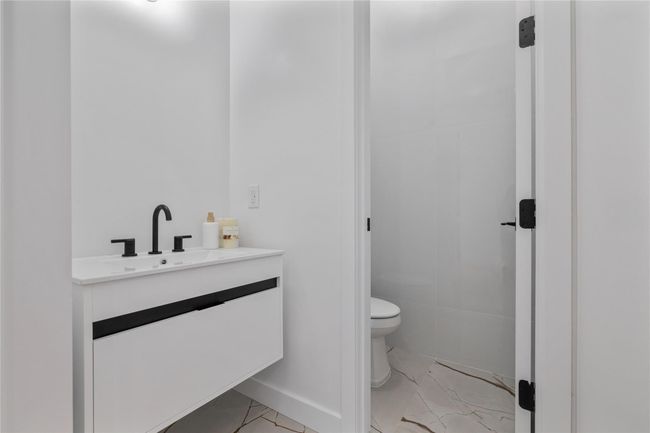 Bathroom with marble finish floor, toilet, vanity, and baseboards | Image 8