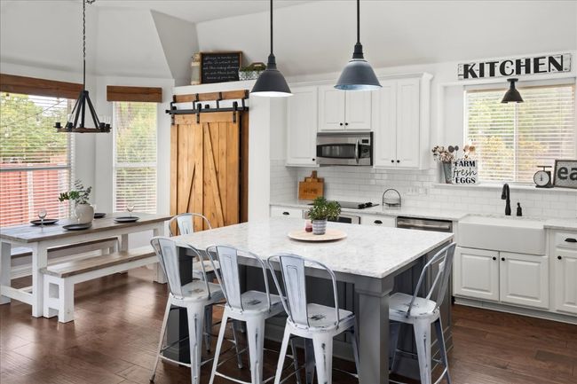 Large island with quartz counters, on-trend pendant lights and farmhouse sink - what a beautiful refresh these sellers did on this kitchen. | Image 8