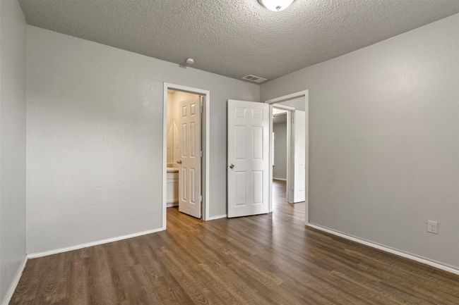 Unfurnished bedroom with dark wood-style flooring, baseboards, and a textured ceiling | Image 24