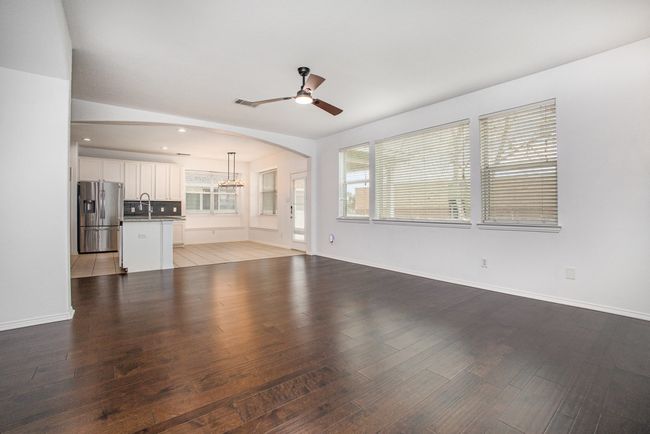 Unfurnished living room featuring baseboards, a wealth of natural light, ceiling fan, and wood finished floors | Image 6