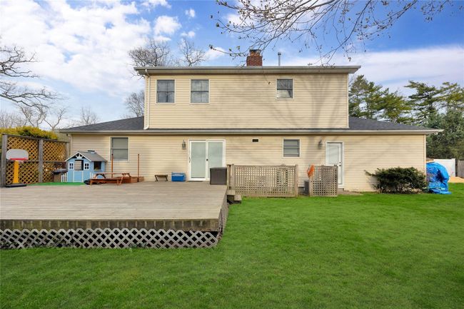 Back of house with a lawn, a wooden deck, and a chimney | Image 22