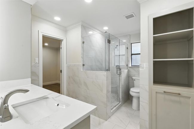 Full bathroom featuring vanity, marble look tiles, a stall shower, ornamental molding, and recessed lighting | Image 29
