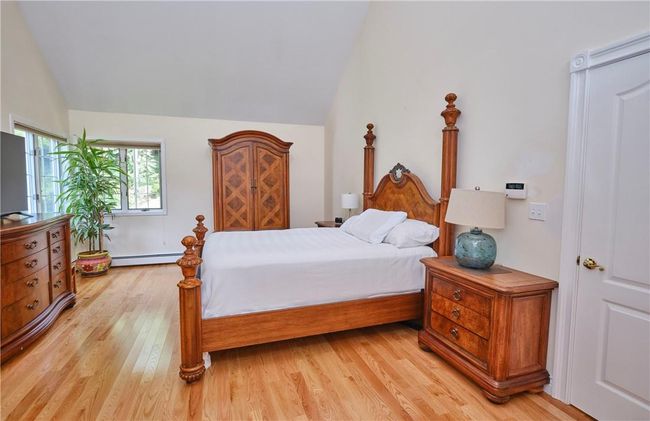 Bedroom with light hardwood / wood-style floors, a baseboard radiator, and lofted ceiling | Image 32