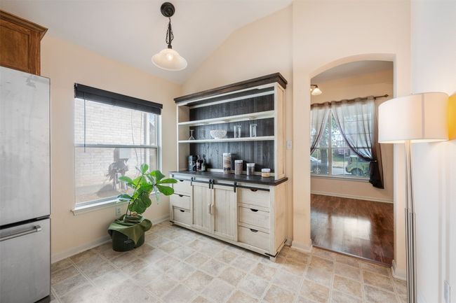 Kitchen featuring decorative light fixtures, dark countertops, freestanding refrigerator, arched walkways, and lofted ceiling | Image 17