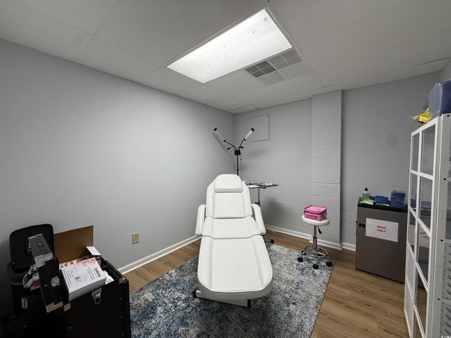 Rec room with wood finished floors, a paneled ceiling, and concrete block wall | Image 6