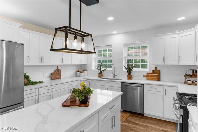 Kitchen featuring appliances with stainless steel finishes, backsplash, white cabinetry, recessed lighting, and wood finished floors | Image 7