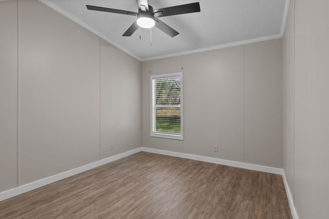 Unfurnished room with wood finished floors, crown molding, a textured ceiling, a ceiling fan, and lofted ceiling | Image 26