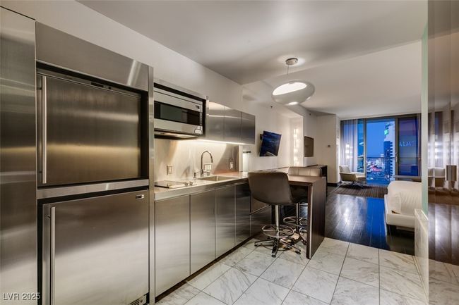 Kitchen with appliances with stainless steel finishes, modern cabinets, light marble finish flooring, light countertops, and open floor plan | Image 4