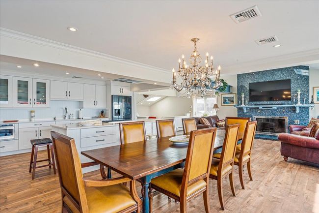 Dining area with a chandelier, light wood finished floors, a premium fireplace, crown molding, and recessed lighting | Image 11