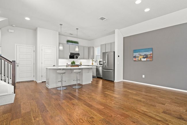 Kitchen with stainless steel appliances, light countertops, a breakfast bar area, a kitchen island with sink, and dark wood finished floors | Image 7