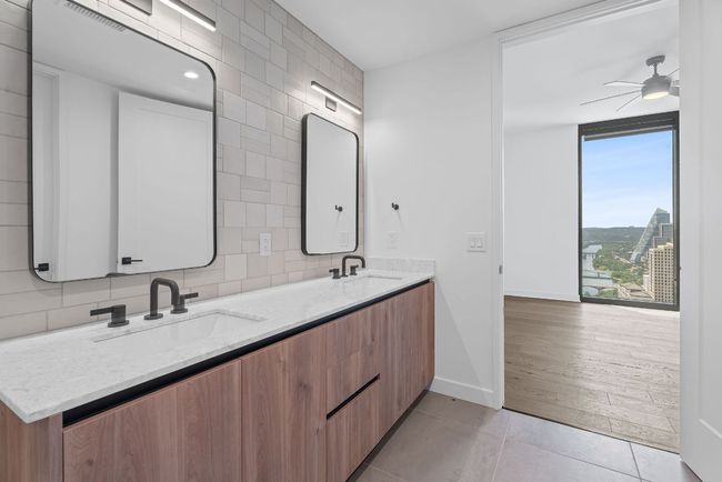Bathroom featuring double vanity, tile patterned floors, a ceiling fan, tile walls, and tasteful backsplash | Image 19