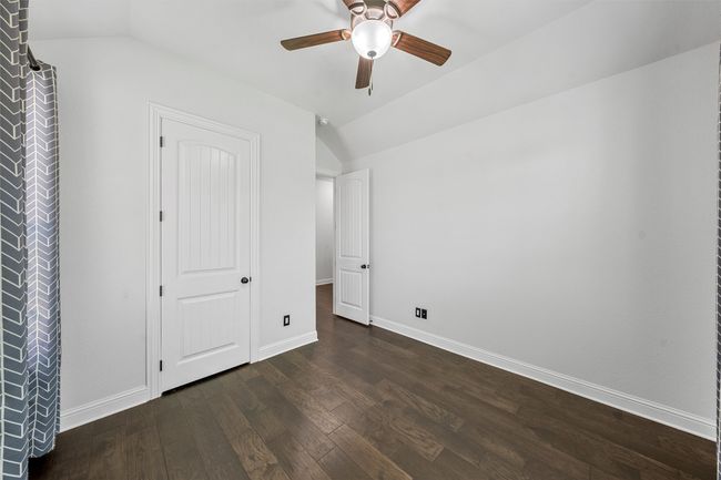Unfurnished bedroom featuring lofted ceiling, dark wood-style flooring, and ceiling fan | Image 24