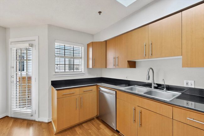 Kitchen with light wood-type flooring, stainless steel dishwasher, a skylight, and light brown cabinets | Image 10