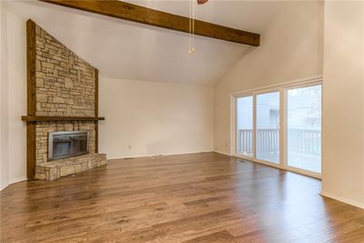 Unfurnished living room with a fireplace, beam ceiling, hardwood / wood-style flooring, and high vaulted ceiling | Image 3