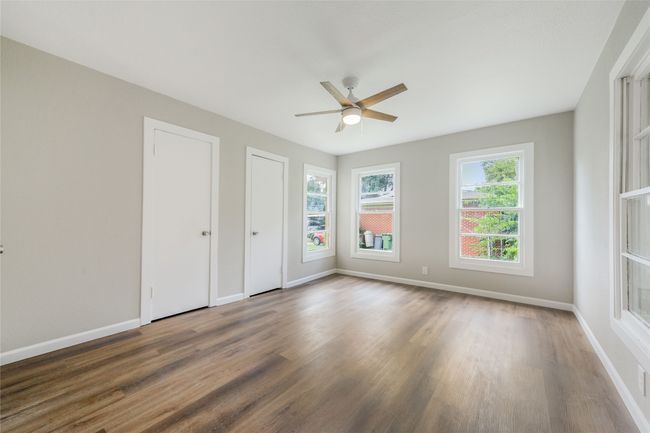 Unfurnished bedroom with wood finished floors, two closets, and a ceiling fan | Image 29