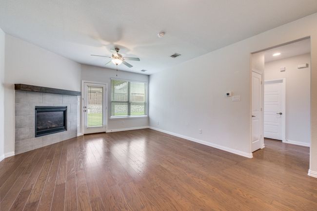 Unfurnished living room featuring wood finished floors, a fireplace, and a ceiling fan | Image 5