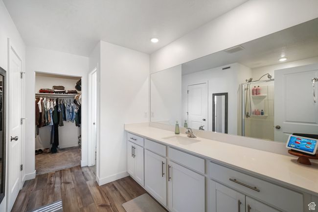 Full bathroom featuring wood finished floors, a spacious closet, vanity, a stall shower, and baseboards | Image 20