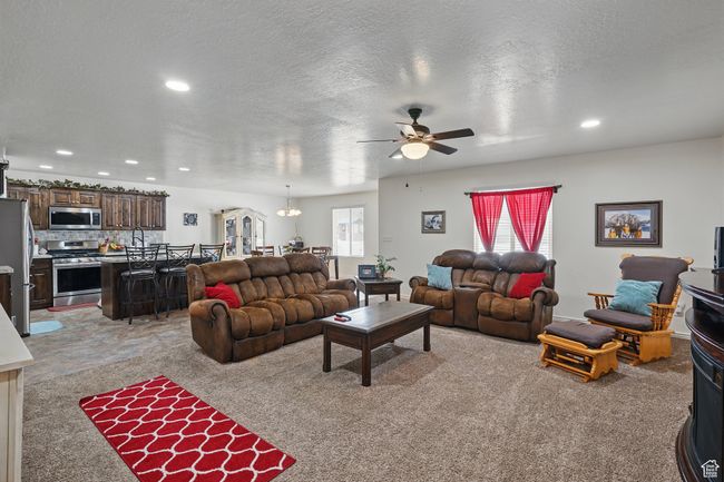 Living room featuring arched walkways, ceiling fan, a textured ceiling, recessed lighting, and light colored carpet | Image 14