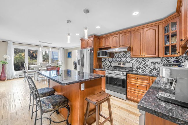 Kitchen featuring stainless steel appliances, a breakfast bar, light wood-type flooring, a center island, and brown cabinetry | Image 15