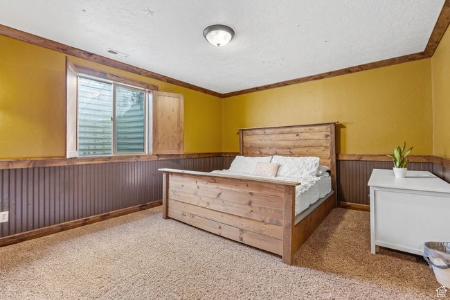 Bedroom featuring crown molding, carpet flooring, a textured ceiling, and wood walls | Image 30