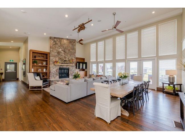 Dining space featuring a stone fireplace, a healthy amount of sunlight, dark wood-style floors, and a towering ceiling | Image 24