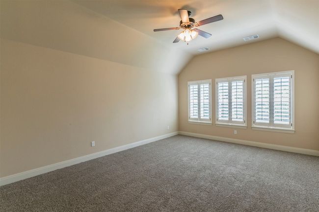 Unfurnished room featuring lofted ceiling, visible vents, a ceiling fan, and carpet floors | Image 31