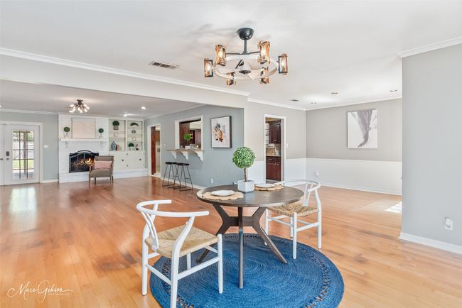 Dining room with crown molding, a fireplace, light wood-type flooring, and a chandelier | Image 5