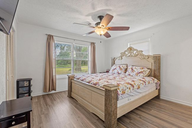 Bedroom featuring a textured ceiling, wood finished floors, crown molding, and ceiling fan | Image 23