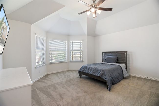 Carpeted bedroom with multiple windows, vaulted ceiling, and ceiling fan | Image 32