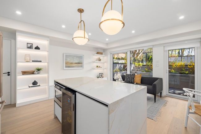 Kitchen with open shelves, beverage cooler, light wood-style floors, a healthy amount of sunlight, and a kitchen island | Image 9