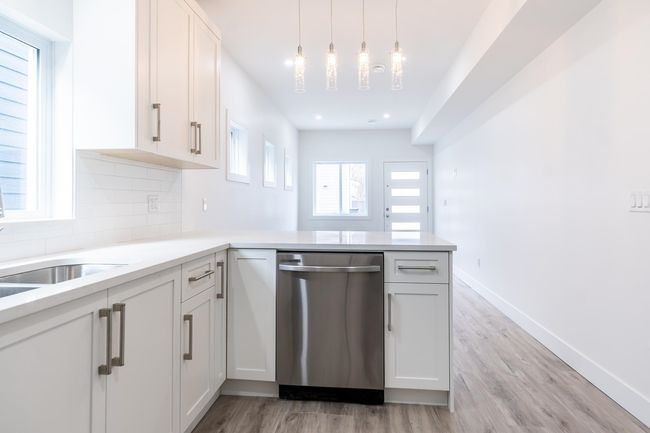 Kitchen with dishwasher, a peninsula, light countertops, light wood-style flooring, and decorative backsplash | Image 11