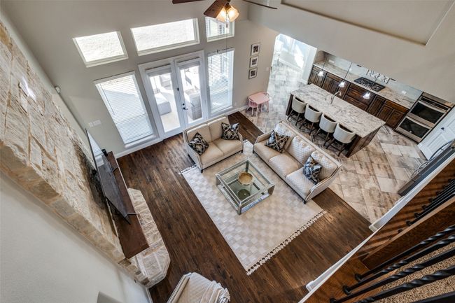 Living room with hardwood / wood-style flooring, ceiling fan, and a high ceiling | Image 5