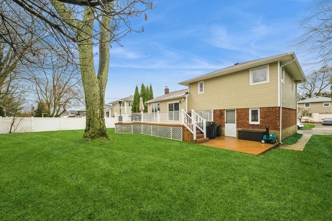 Rear view of house with a lawn, brick siding, fence, and a wooden deck | Image 26