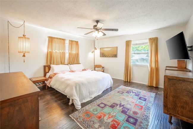 Bedroom featuring a textured ceiling, ceiling fan, baseboards, and dark wood finished floors | Image 12